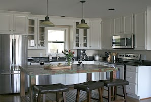 A modern kitchen with white cabinets, stainless steel appliances, and a central island with bar stools.