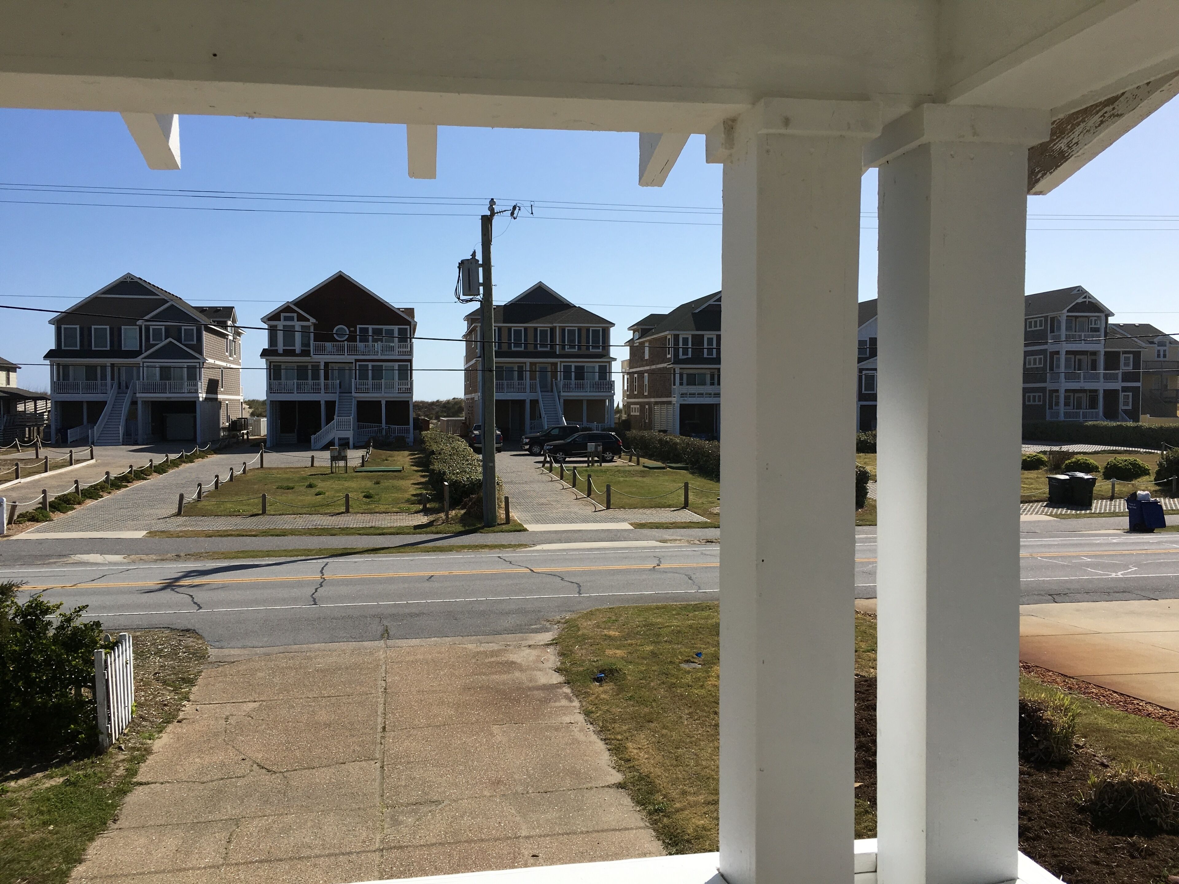 A residential area with multiple two-story houses, a paved road, and a sidewalk.