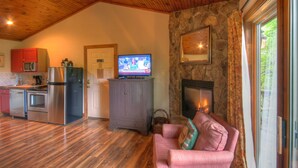 A cozy living room with a fireplace, a television, and a stone wall. - Vacation Cottage in Premier Resort (Boone)