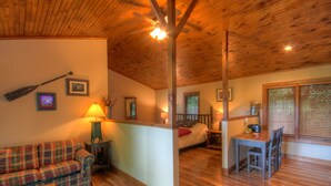 A cozy cabin interior with a plaid sofa, wooden dining table, and a bed with a wooden headboard. - Vacation Cottage in Premier Resort (Boone)