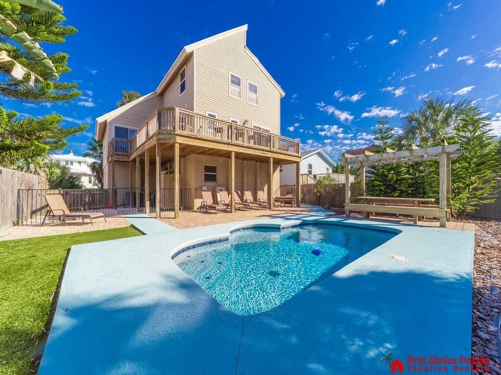 Une maison à deux étages avec une piscine et un patio couvert.