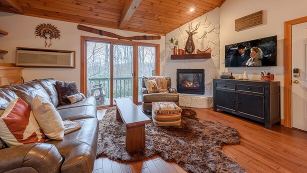Una sala de estar acogedora con chimenea, sofá de cuero y televisor montado en la pared.