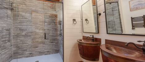 A modern bathroom with a glass shower enclosure, wooden vanity, and a large mirror.