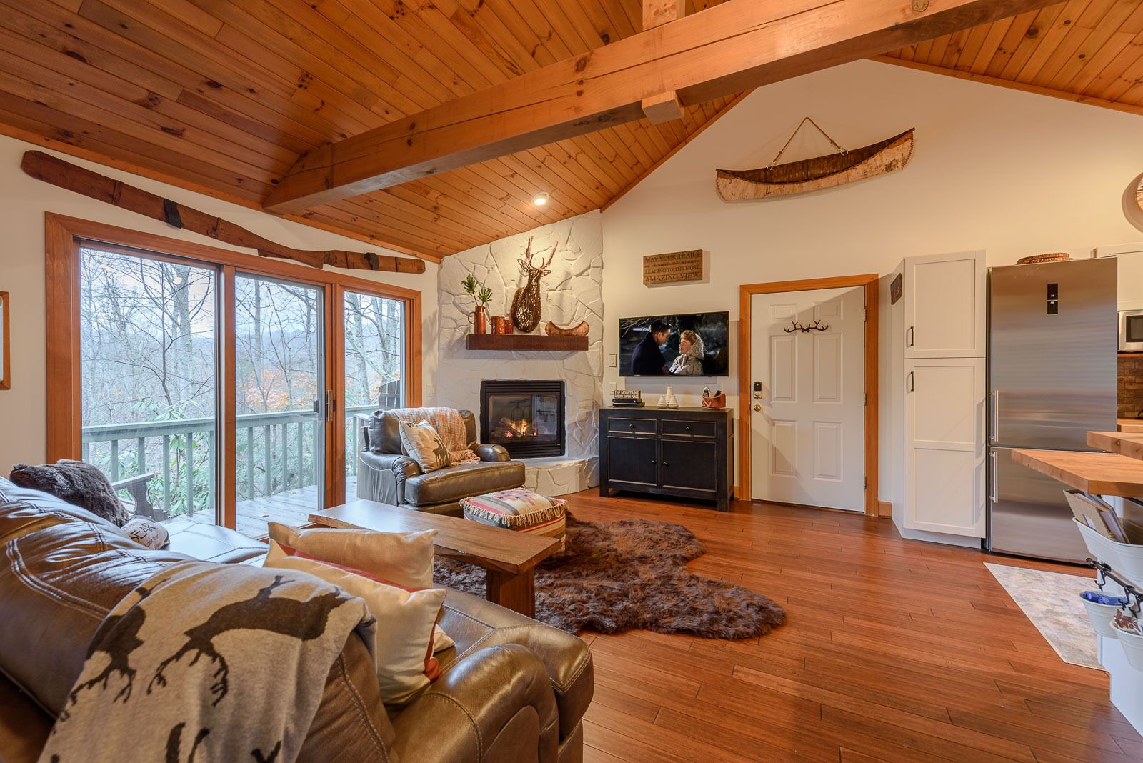 A cozy living room with a fireplace, leather sofa, and a television.