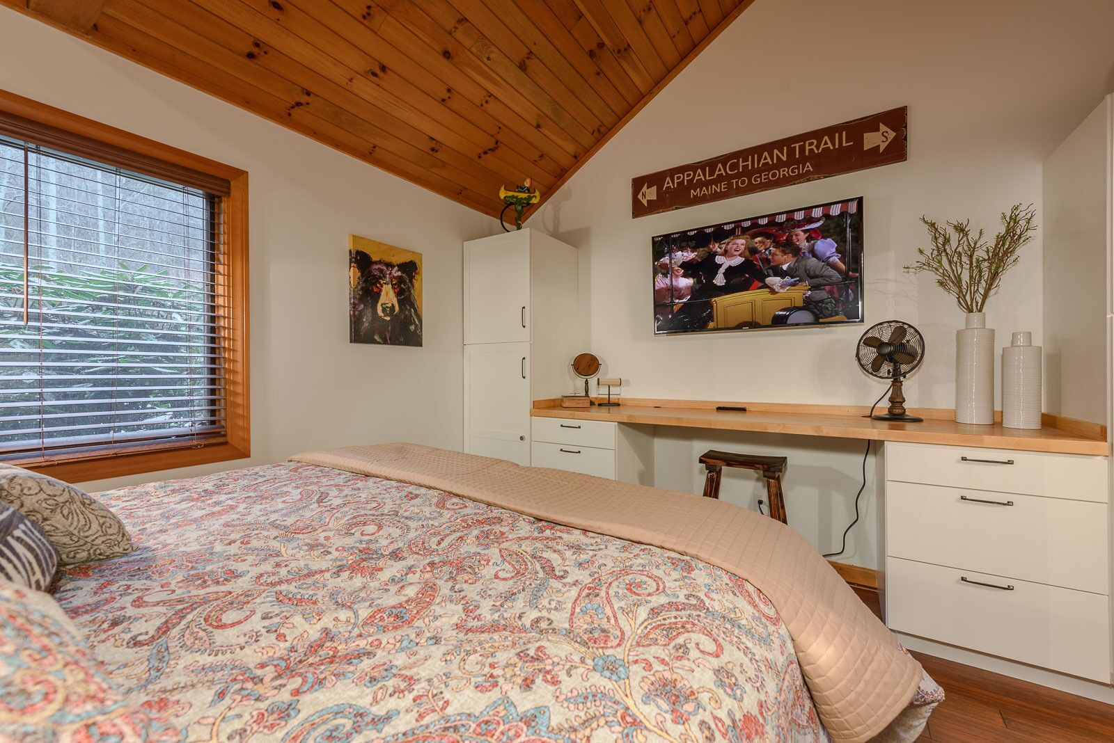 Una camera da letto con un letto, una scrivania in legno, una televisione e un cartello che indica il sentiero Appalachian.