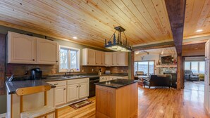 A spacious kitchen with wooden cabinets, a central island, and a dining area with a view. - Mountain View Lodge on Seven Devils (Seven Devils)