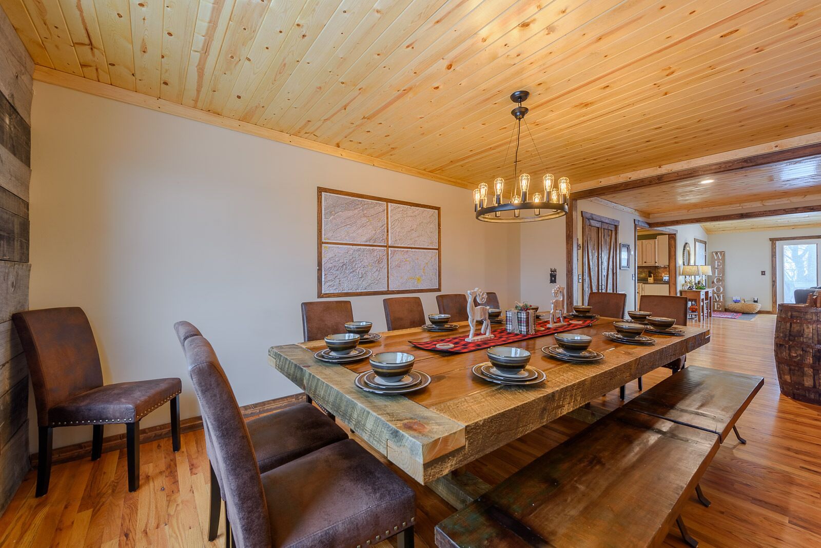 A spacious dining area with a long wooden table set for a meal, surrounded by leather chairs.