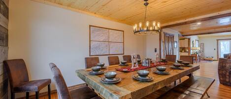 A spacious dining area with a long wooden table set for a meal, surrounded by leather chairs.