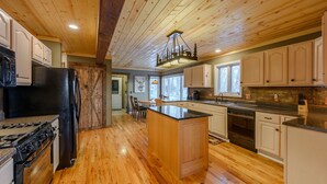 A spacious kitchen with wooden floors, a central island, and a large chandelier. - Mountain View Lodge on Seven Devils (Seven Devils)