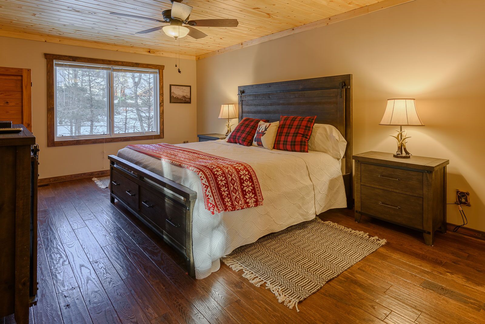 A bedroom with a bed, a nightstand, a dresser, a window, and a ceiling fan.