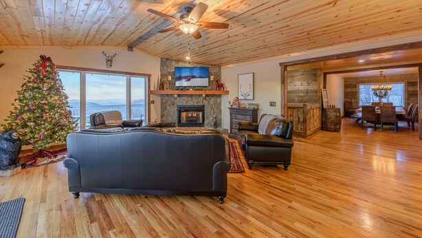 A cozy living room with a fireplace, a large TV, and a Christmas tree. - Mountain View Lodge on Seven Devils (Seven Devils)