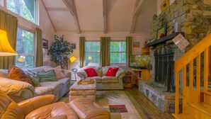 A cozy living room with leather sofas, a fireplace, and a stone wall. - Peaceful Chalet Close to Skiing (Beech Mountain)