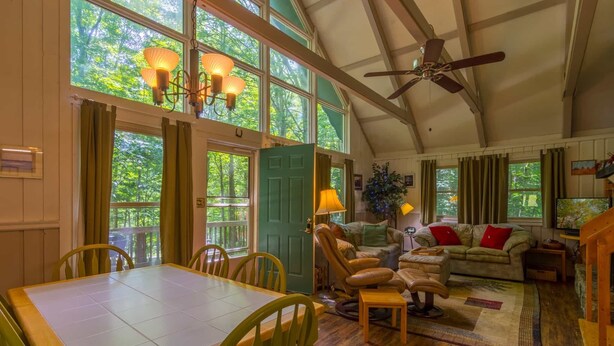 A cozy living room with a dining area, large windows, and a ceiling fan. - Peaceful Chalet Close to Skiing (Beech Mountain)