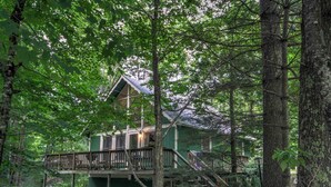 A treehouse with a wooden deck and stairs, surrounded by dense forest. - Peaceful Chalet Close to Skiing (Beech Mountain)