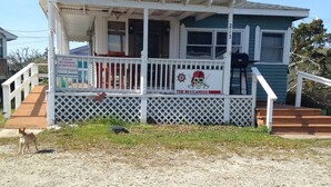 A two-story house with a porch, a sign indicating no parking in driveways, and a grill on the porch. - The Buccaneer-Cottage, great for a couple or small family. (Ocracoke)