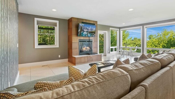 A modern living room with a fireplace, a large TV, and a sofa with patterned cushions. - Luxury Home with In-law Apartment (Boone)