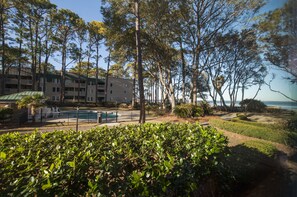 A hotel with a pool, surrounded by trees and a view of the ocean.