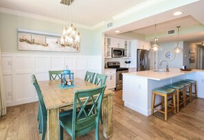 A kitchen with white cabinets, a wooden island, and bar stools.