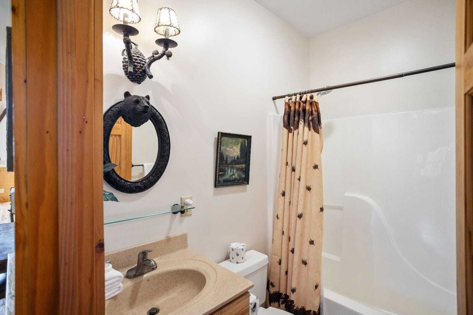 Een badkamer met een wastafel, spiegel en douchegordijn.