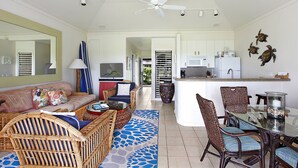 A spacious living area with a sofa, wicker chairs, a dining table, and a kitchen area with a refrigerator and microwave. - Kiahuna Plantation 165 By Parrish Kauai - ocean view unit, only steps to the bea (Koloa)