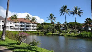 A hotel with multiple-story buildings, a pond, and palm trees. - Kiahuna Plantation 165 By Parrish Kauai - ocean view unit, only steps to the bea (Koloa)
