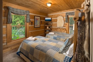 A cozy cabin room with a bed, a television, and a map on the wall.