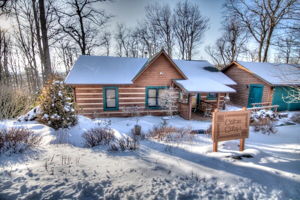 A cabin with a snow-covered roof, a porch, and a sign indicating it is a Celtic Cabin.