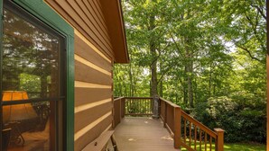 A wooden deck with a railing leading to a building with a large window.