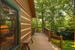 A wooden deck with a railing leading to a building with a large window.
