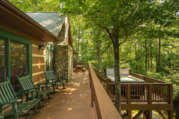 A wooden deck with outdoor seating and a stone wall.