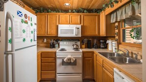 A kitchen with wooden cabinets, a white stove, a microwave, and a sink.