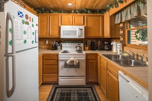 A kitchen with wooden cabinets, a white stove, a microwave, and a sink.