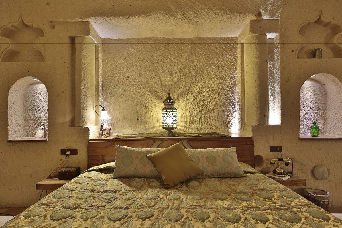 Uma cama com colcha estampada, um travesseiro e uma luminária na parede.