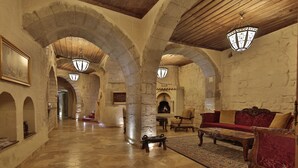 Un pasillo amplio con arcos de piedra, una chimenea y un sofá rojo.