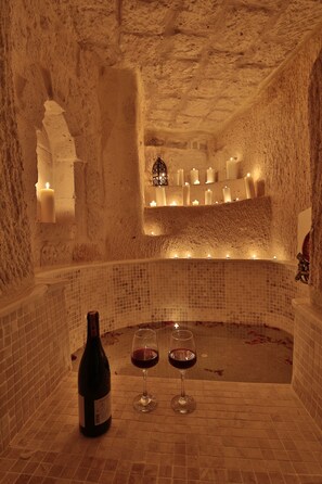 An ice bath with candles, a bottle of wine, and glasses on a tiled floor. - Romance Cave Suites (Nevsehir)