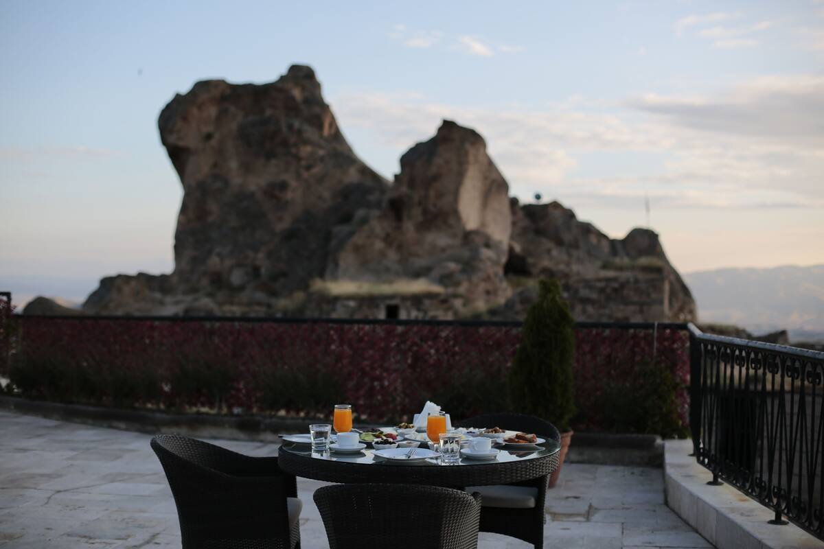Mesa posta para o pequeno-almoço com vista para falésias rochosas.