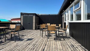 Eine Holzterrasse mit Sitzgelegenheit und einem Geräteschuppen.