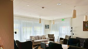 Ein modernes Wohnzimmer mit einer Couch, Sesseln, einem Couchtisch und einem Esstisch.