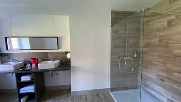 Un baño moderno con dos lavamanos, cabina de ducha de cristal y pared de madera.