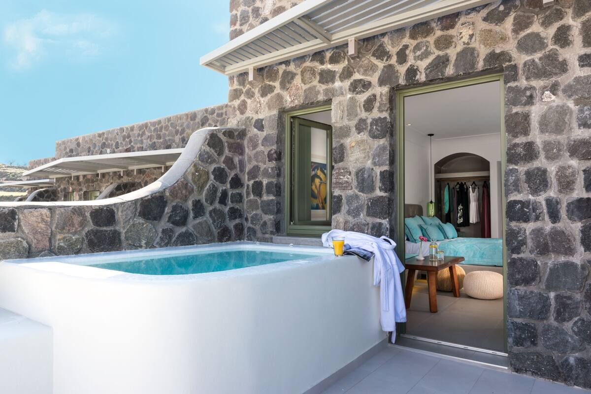 A stone exterior with a hot tub, a door leading to a room with a bed and a closet.
