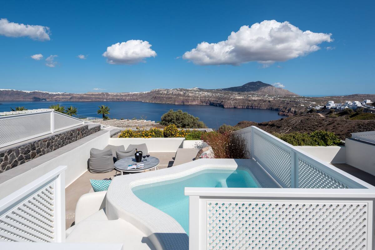 A rooftop pool area with a view of the sea and a mountain in the distance.