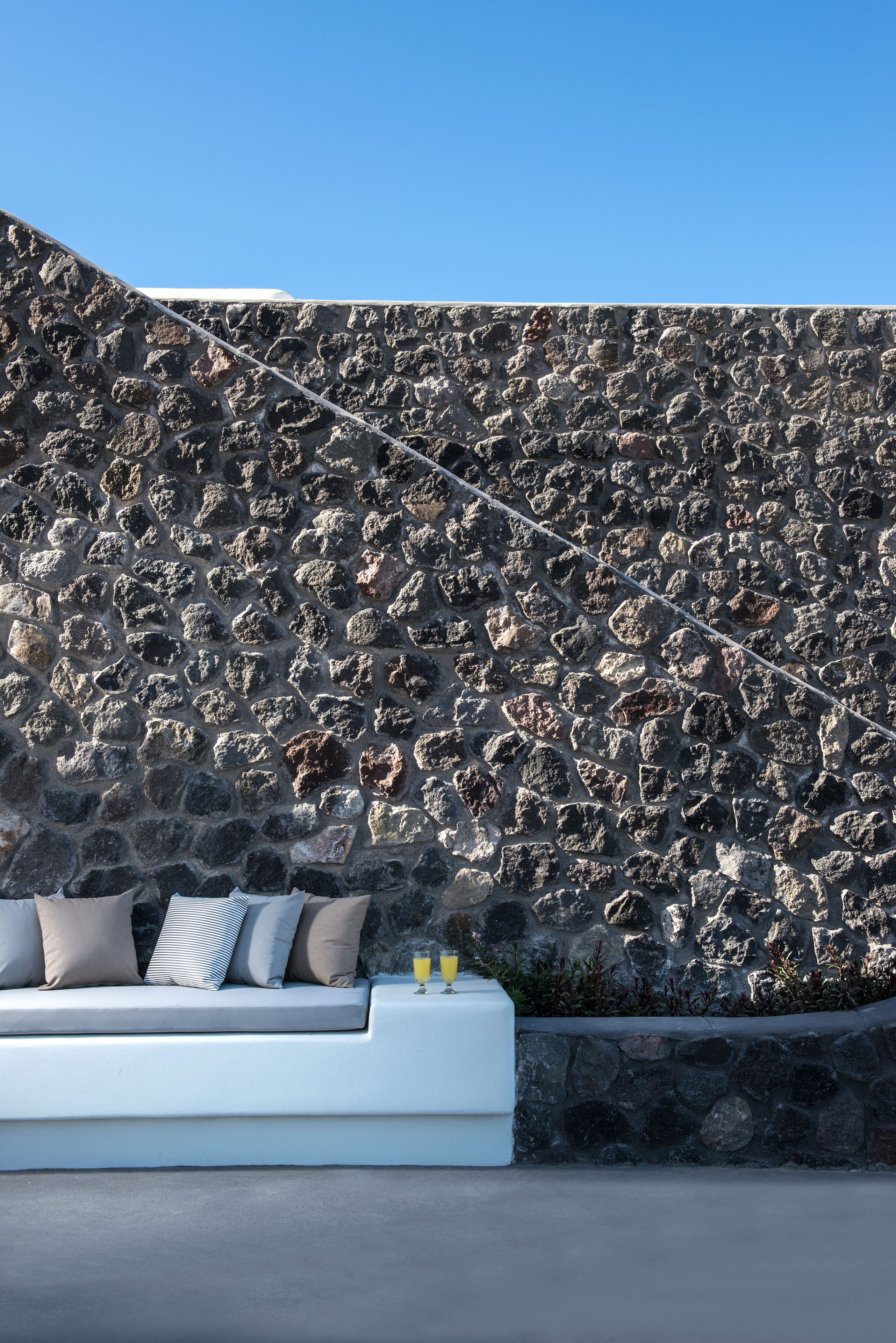 A stone wall with a modern sofa and cushions.