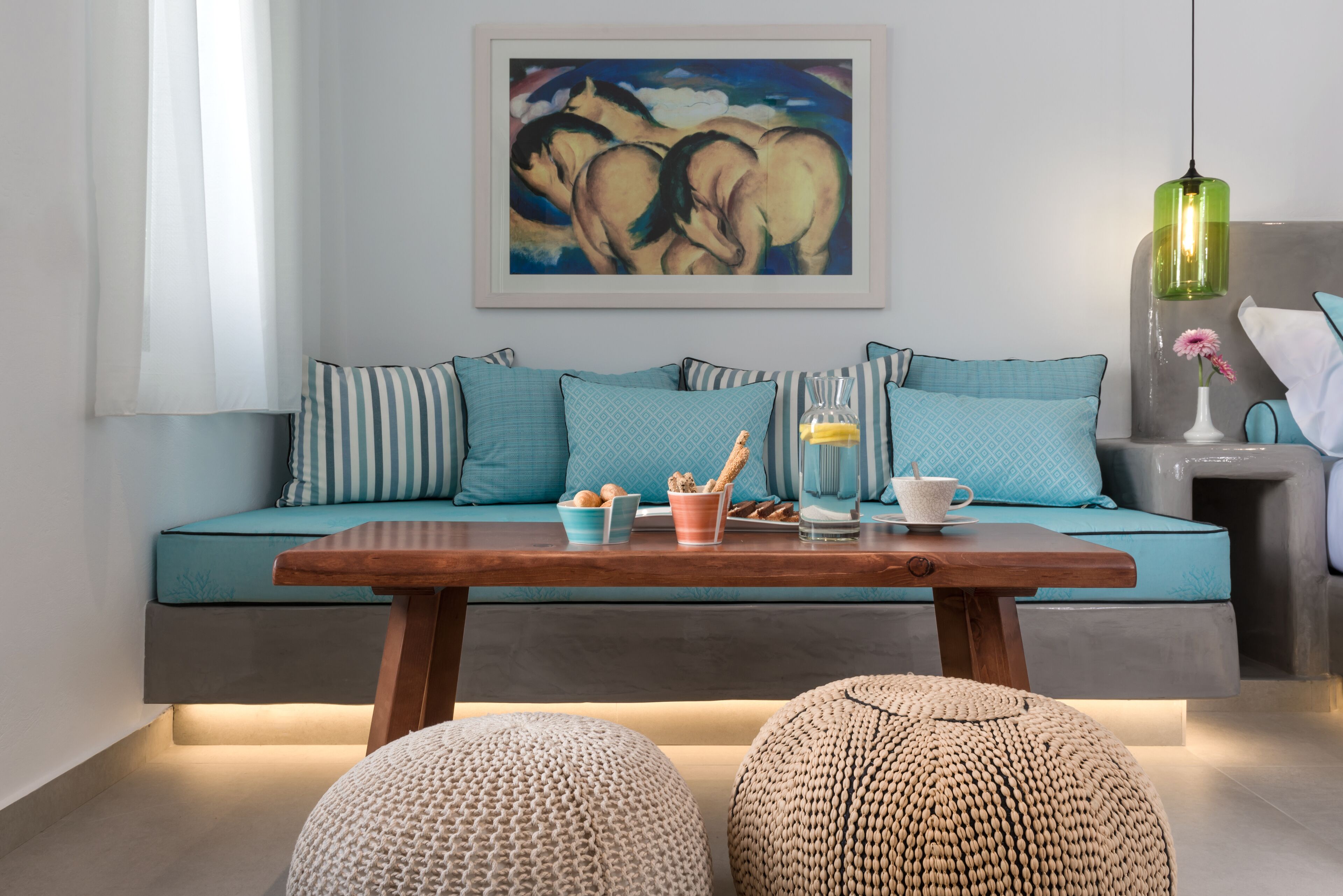 Uma sala de estar moderna com um sofá, almofadas, uma mesa de centro e um quadro na parede.