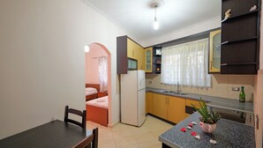 Una cocina compacta con refrigerador, lavamanos y un comedor con mesa y sillas.