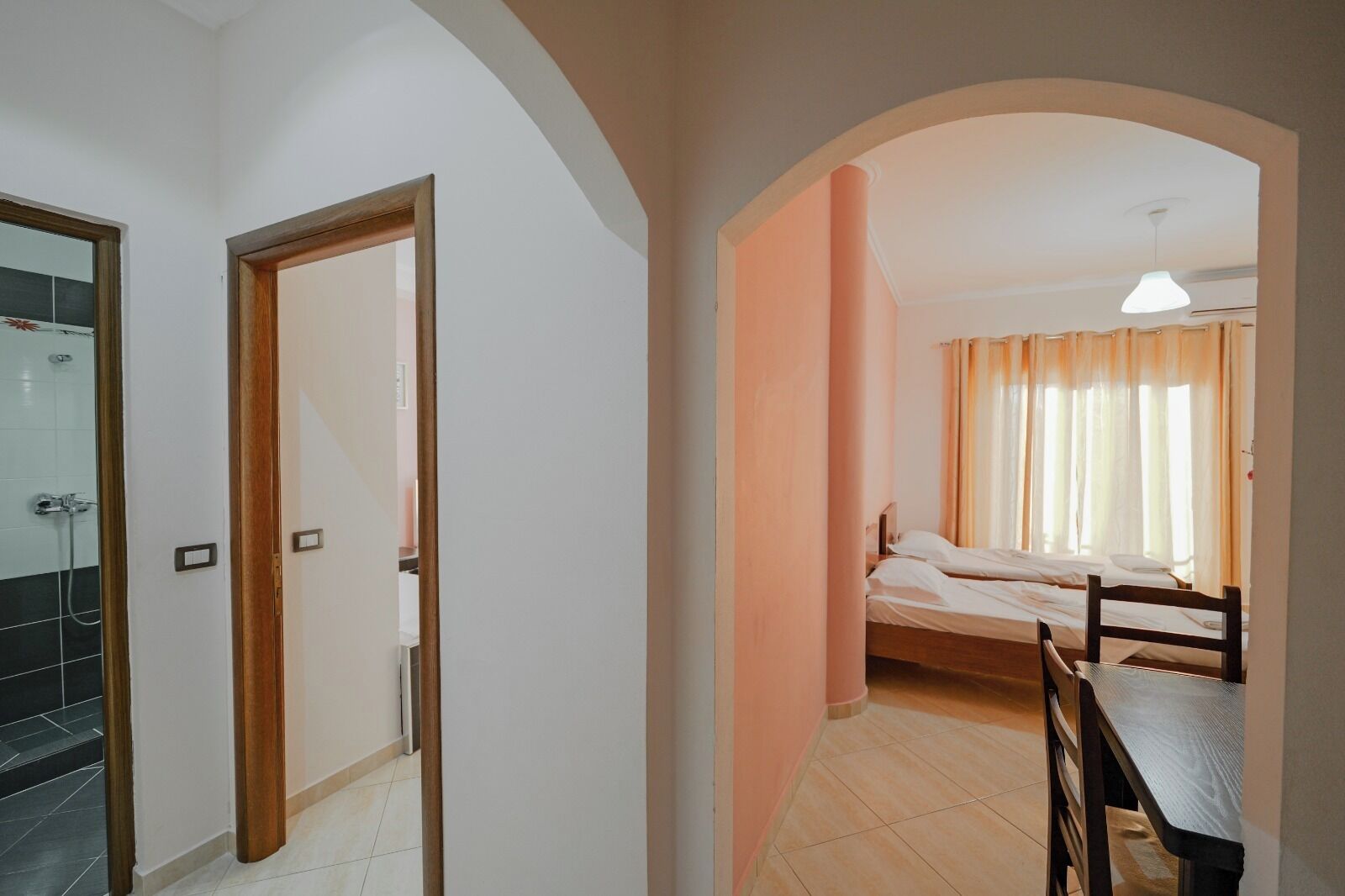 A hotel room with a shower, a bed, a table, and a chair.