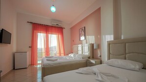 Una habitación de hotel con dos camas, televisión, aire acondicionado y un balcón con vistas.