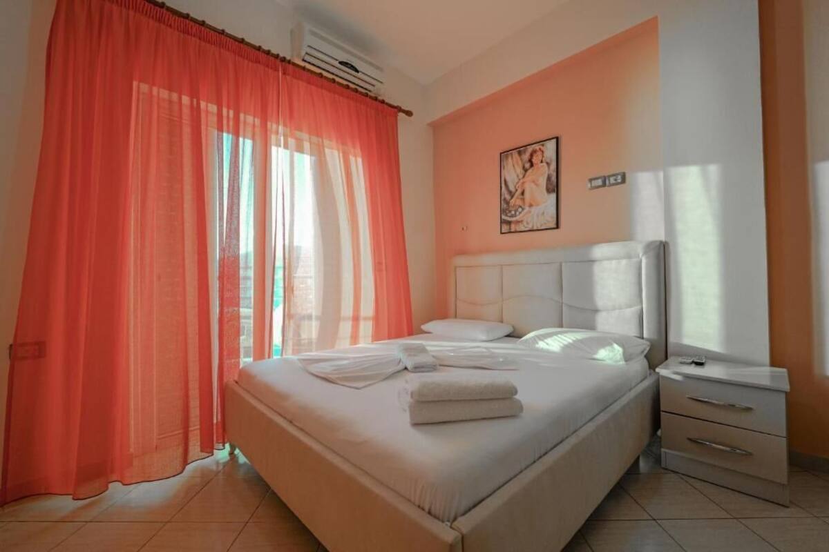 A bedroom with a bed, a nightstand, and a painting on the wall.