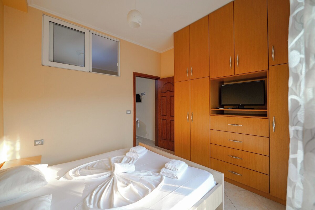 A hotel room with a bed, wooden wardrobe, and a television.