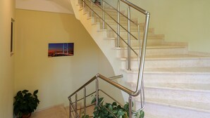 Una escalera con barandilla de metal, una planta en maceta y un cuadro en la pared.