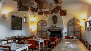 Un restaurant avec une longue table en bois, des chaises rouges et des paniers suspendus.